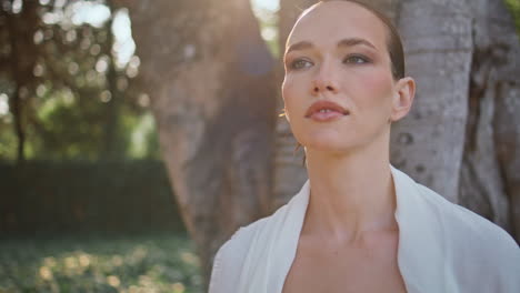 hermosa modelo posando jardín mirando a la naturaleza belleza de cerca. mujer bajo el árbol