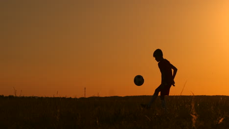 Silhouette-Eines-Jungen,-Der-Bei-Sonnenuntergang-Fußball-Spielt.-Ein-Junge-Jongliert-Bei-Sonnenuntergang-Auf-Dem-Feld-Mit-Einem-Ball.