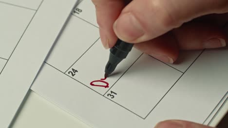 mujer marcando el día en el calendario escribiendo médico como recordatorio usando un marcador rojo