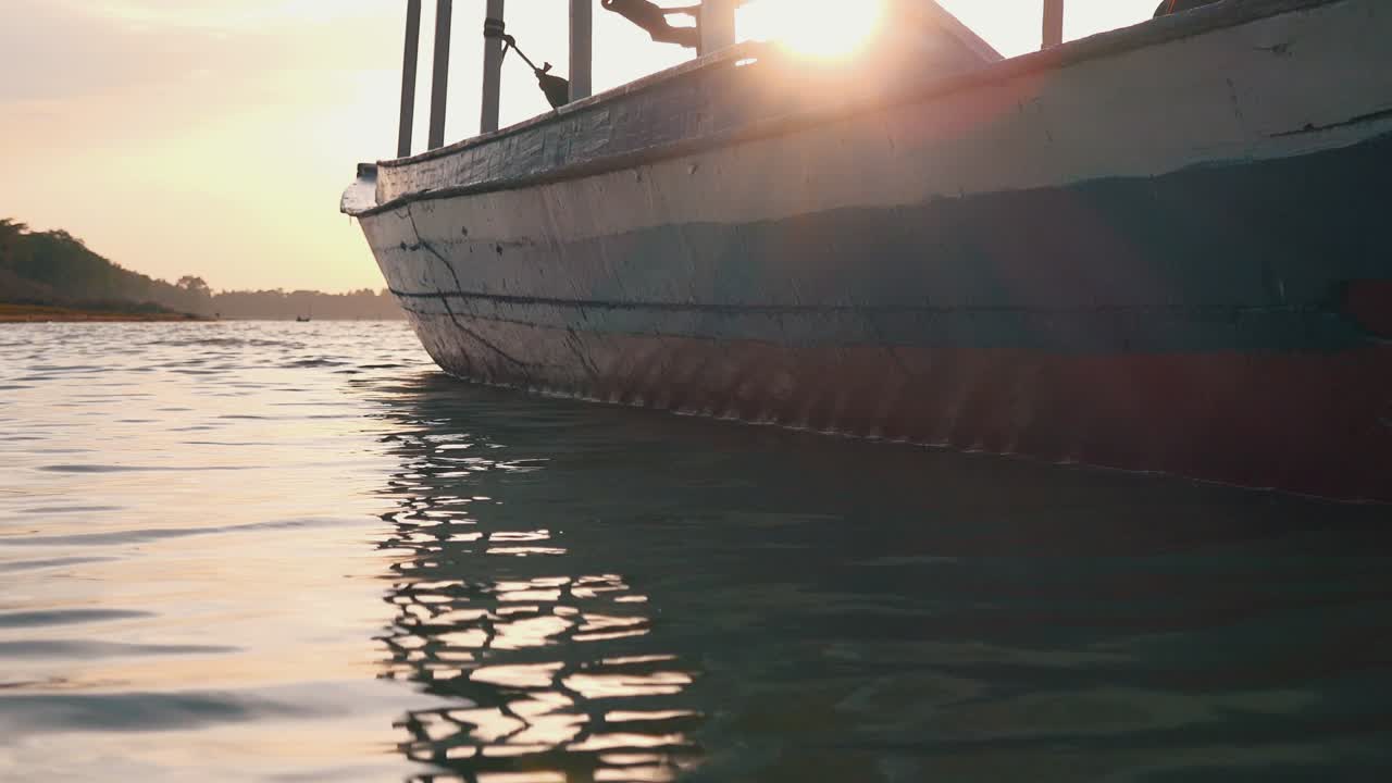 sol parpadeando detrás de un bote en el agua al atardecer
