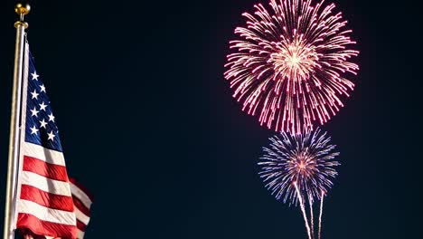 A low-angle shot of the American flag waving against a backdrop of vibrant fireworks