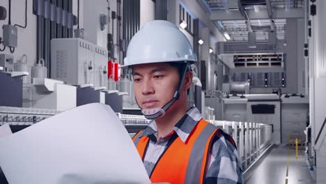 close up side view of asian male engineer with safety helmet looking at blueprint in his hands and looking around while standing at pharmaceutical factory, vaccine production facility