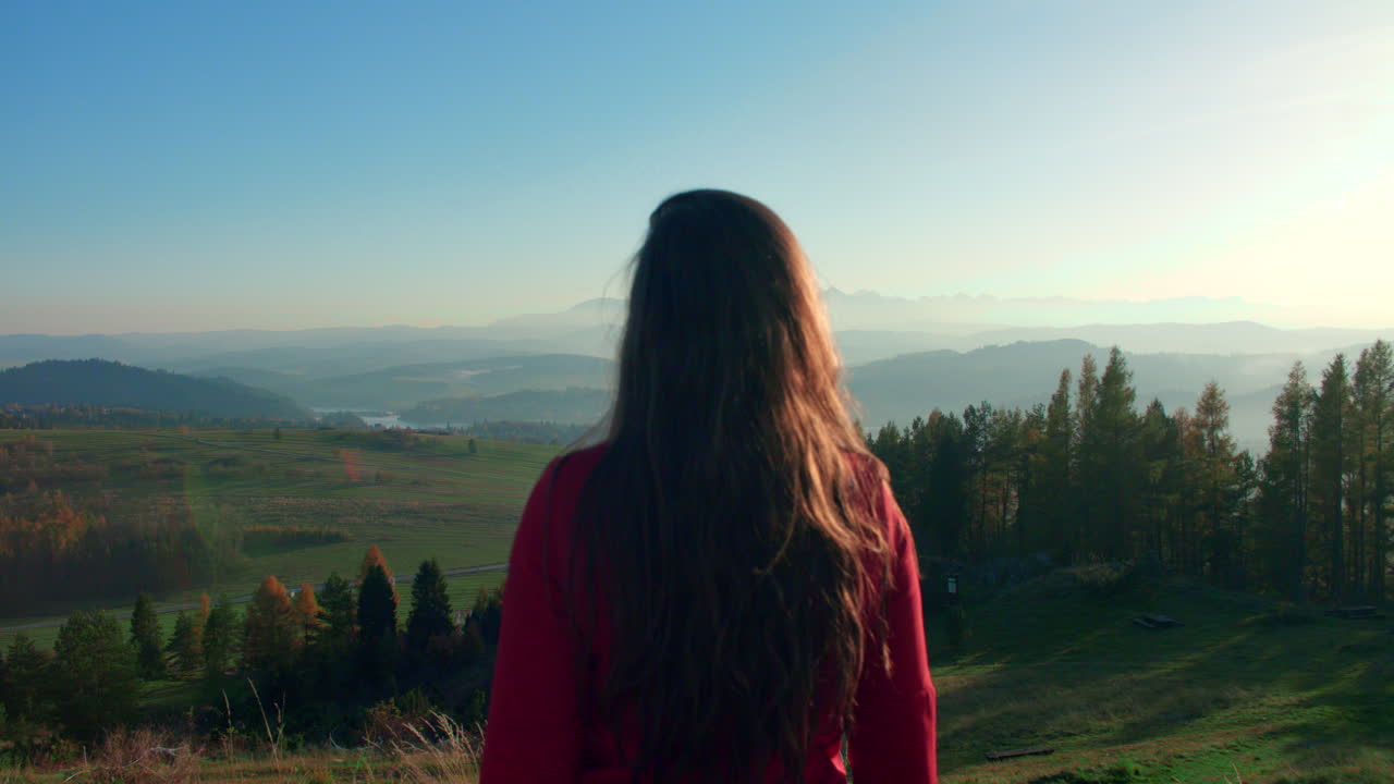 lonely girl standing and looking at hilly landscape on a sunny day