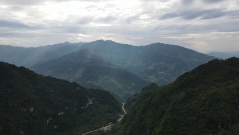 Arial-view-of-small-mountain-pass-between-mountain-ranges-with-majestic-mountain-background-with-sunbeam-shining-down