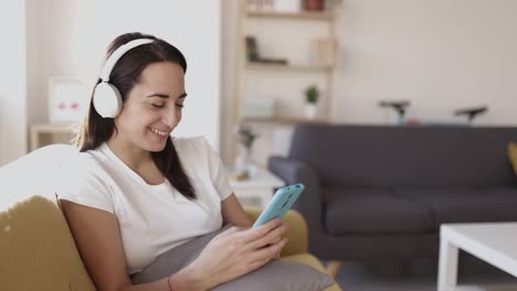 joven adulta feliz y positiva usando el teléfono mientras escucha música en casa
