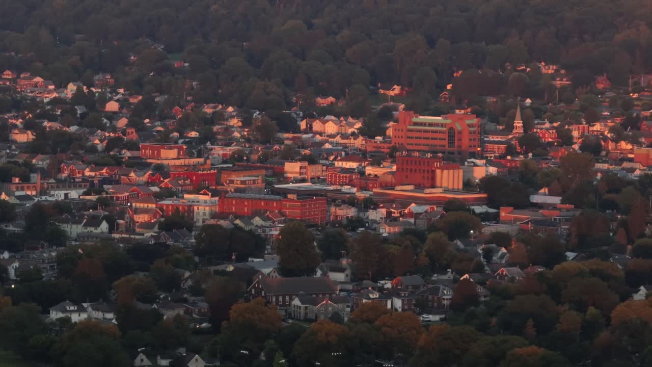Golden lighting red brick buildings in downtown of small American town during golden hour. Aerial zoom wide shot. Ephrata, Pennsylvania in summer season
