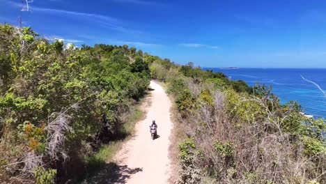 freedom travel adventure, man exploring philippines coastal on motorbike, rural. drone following