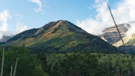 a mountain in autumn with clouds swirling between