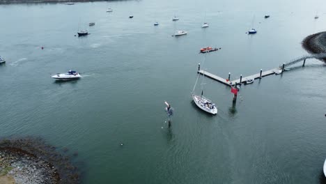 aerial view above boat leaving wealthy yacht marina navigating luxury expensive sailboat waterfront