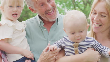 retrato de abuelos sonrientes con madre y nietos en casa en el jardín juntos