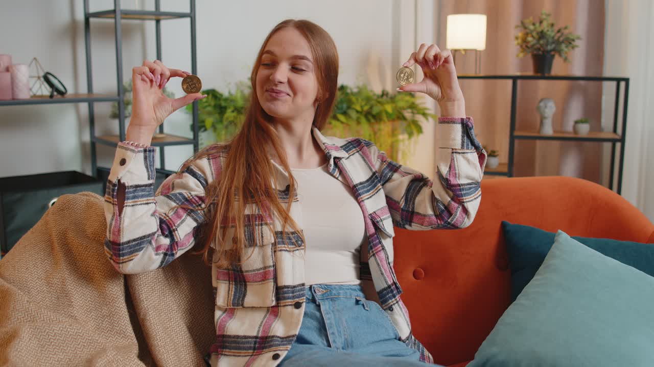 Woman freelancer holding two gold coins btc at home successful developer programmer stock trader