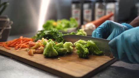 chef slicing broccoli on kitchen cutting board