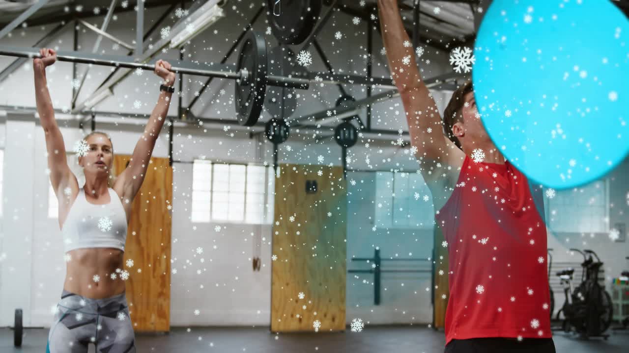 Mentre afferrano il bilanciere, uomo e donna eseguono un clean press durante l'allenamento in palestra, con sovrapposizioni di fiocchi di neve.