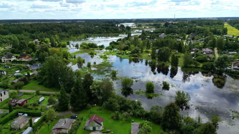 drone shot of flooded and overflowing river at a small village with trees on a cloudy day