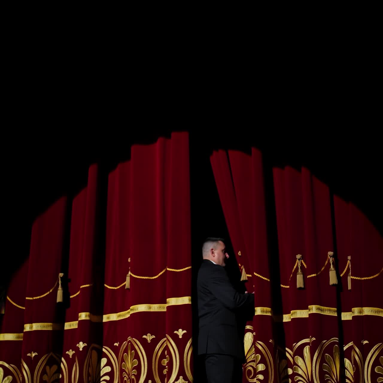 Attore sul palco di un teatro classico. Uomo dopo lo spettacolo lascia il palco sotto i riflettori. Video con vista posteriore.