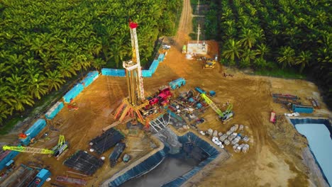 Cinematic-4K-Drone-Footage-of-Onshore-Drilling-Rig-equipment-structure-for-oil-exploration-and-exploitation-in-the-middle-of-jungle-surrounded-by-palm-oil-trees-during-sunset-and-high-oil-price