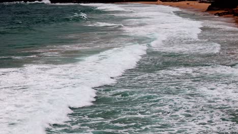 Küstenwellen,-Die-Sich-Rhythmisch-Einem-Sandstrand-Nähern,-Ein-Tanz-Von-Meer-Und-Küste-Unter-Einem-Bewölkten-Himmel