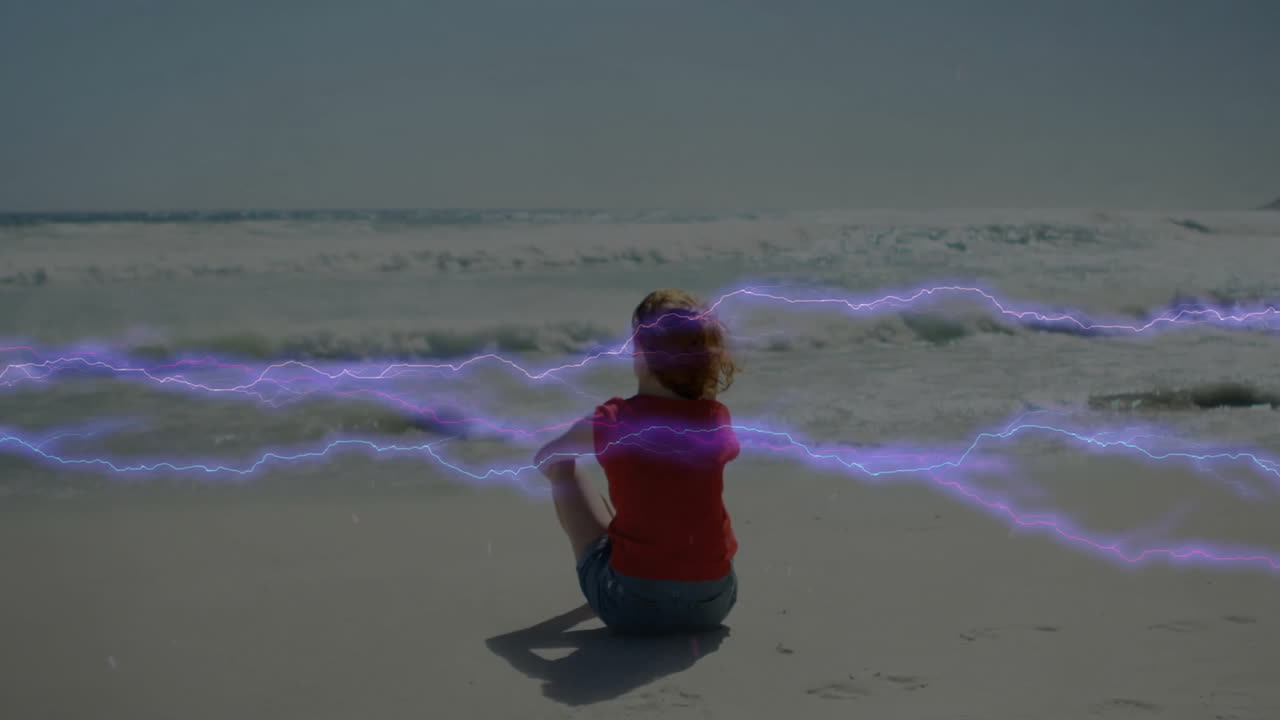 Child sitting on beach with purple lightning animation over ocean waves