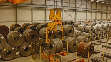 wide view of an automated bridge crane picking up a steel coil from a transport system in a automated warehouse