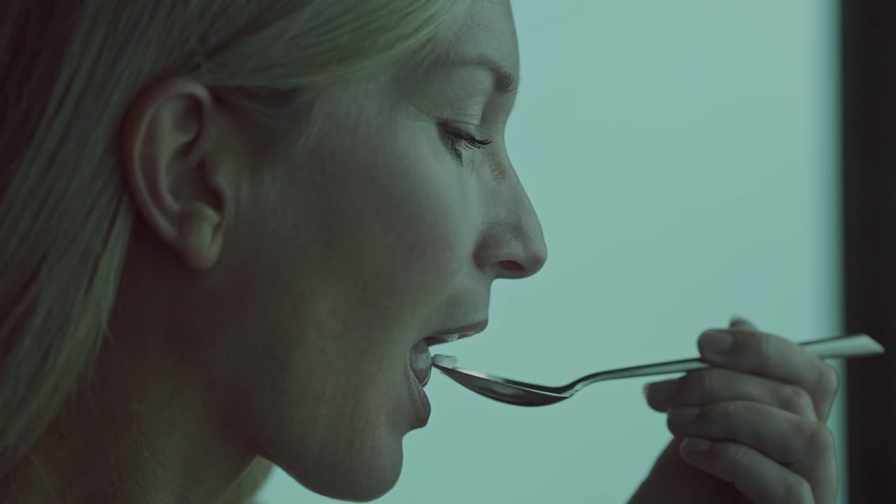 Close up of attractive woman tasting food from spoon with joyful expression