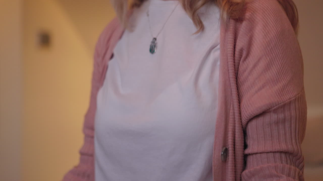 A woman wearing a pink cardigan and white t-shirt