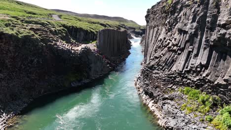 basalt columns in studlagil canyon in east iceland on sunny day - drone shot