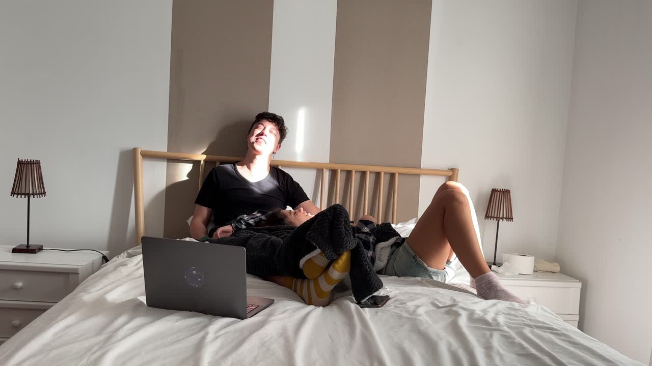 Couple Relaxing on Bed Watching Laptop