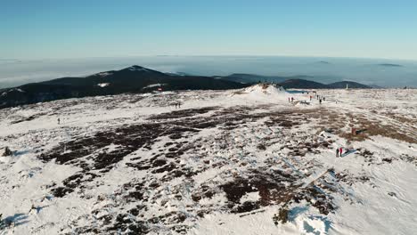 people hiking on top of czech mountain covered with snow from drone