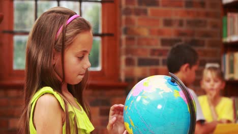 niña mirando el globo en la biblioteca