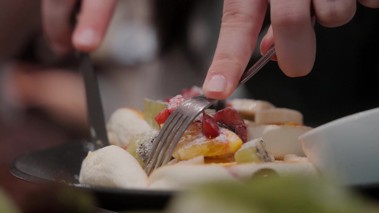 Close view of hands cutting fruit dessert inside restaurant in Tokyo Japan
