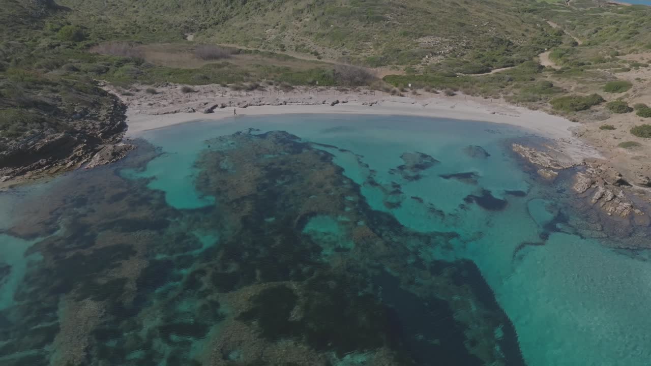 drone aéreo se aleja de la bahía de agua de la playa turquesa en cala sa torreta españa destino de viaje, entorno natural