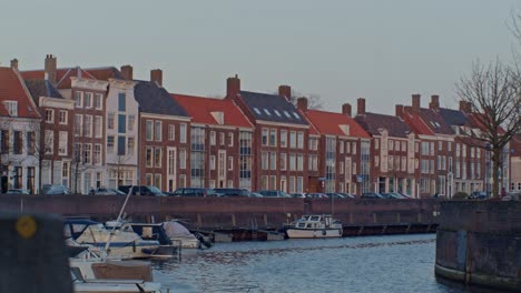 Una-Hermosa-Vista-Cinematográfica-De-Una-Calle-Europea-En-Holanda,-Holanda,-Con-Casas,-Canales-De-Agua,-Barcos-Y-Una-Auténtica-Arquitectura-De-Estilo-Holandés-Con-Puesta-De-Sol-Y-Luz-Solar.