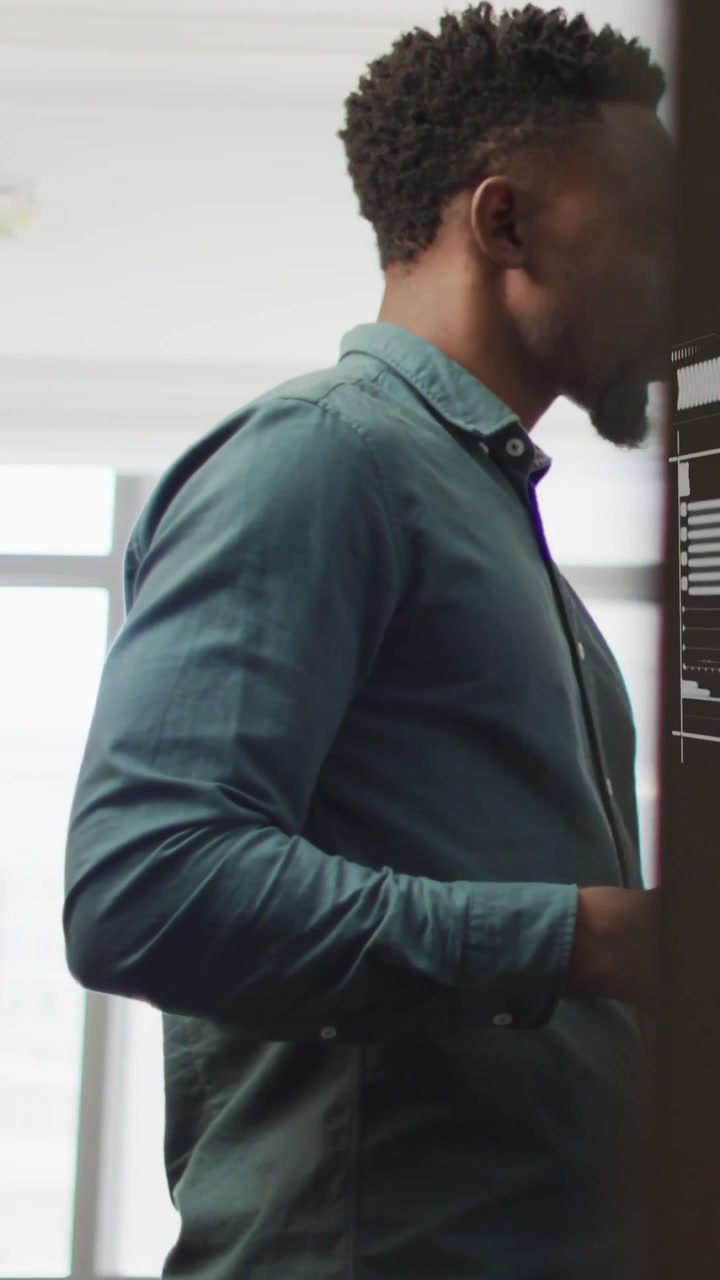 Vertical video: Man in teal shirt entering while door shifting, operating wall printer for office