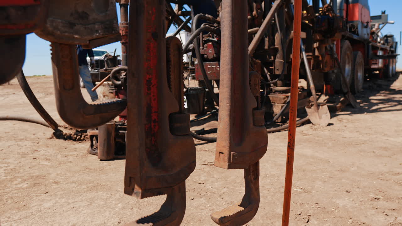 Diverse equipment at the drilling site in the deserted area. Two men work at oil and gas production.