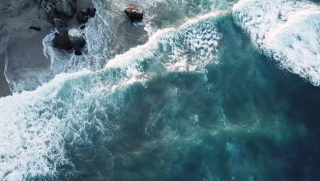 the-blue-and-translucent-waves-smashing-into-the-rocks-on-a-windy-day