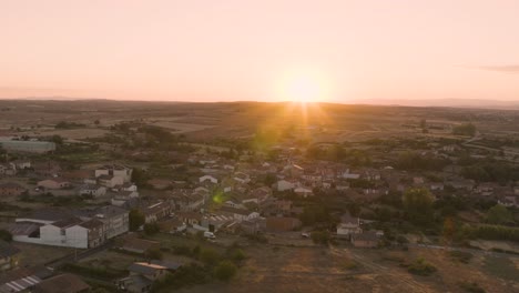 Paisaje-Aéreo-De-Pequeñas-Casas-De-Pueblo-En-Un-Valle-Rural-Con-Puesta-De-Sol-En-El-Horizonte