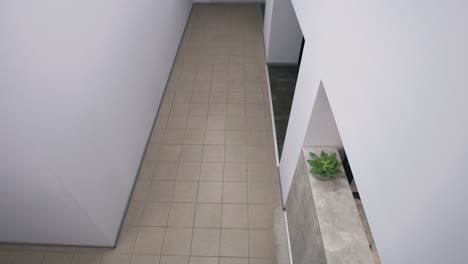 overhead view of a man in a modern office hallway with white walls and tiled floors