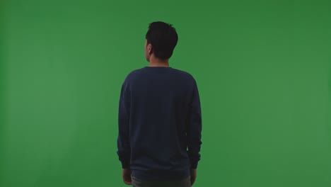 back view of distressed asian refugee male standing and looking around protects himself from the war on the green screen background