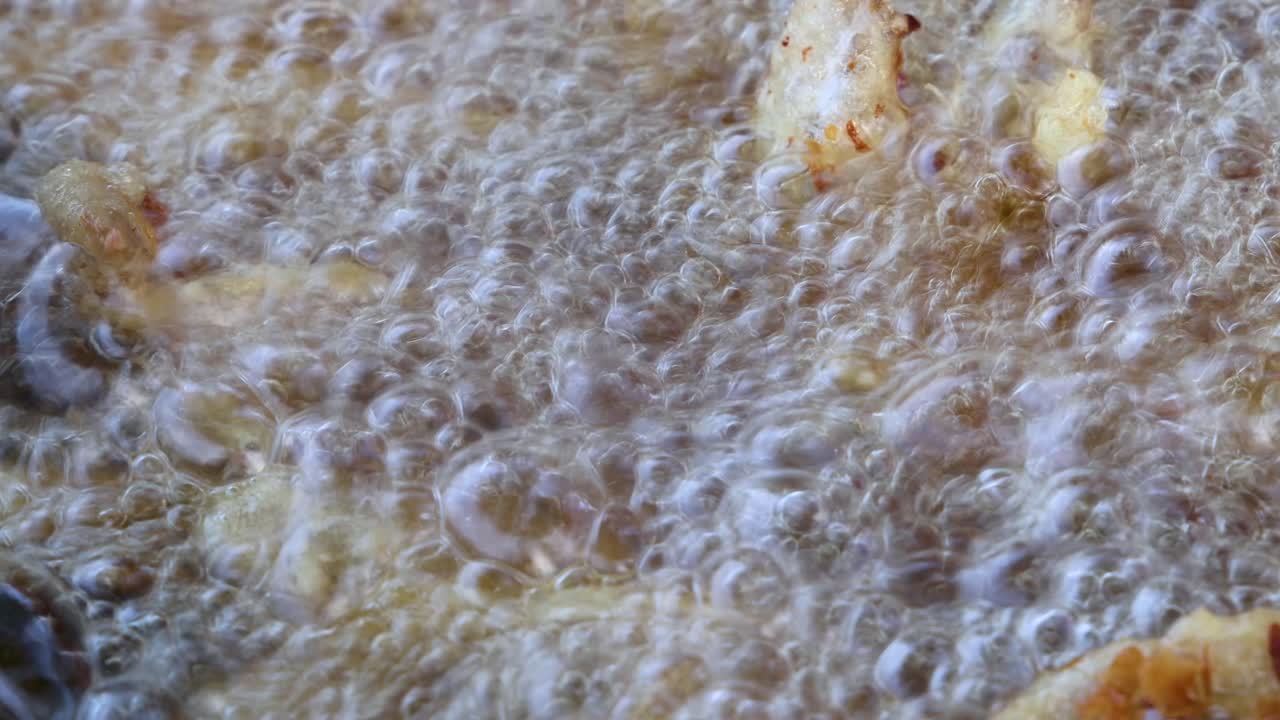 Golden potato fries frying in bubbling oil, extreme close-up, natural lighting, static camera shot
