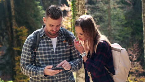 couple hiking and using smartphone for navigation in forest