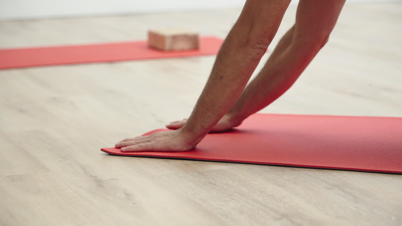 Persona desenrollando colchoneta de yoga y apoyando las manos en el suelo.