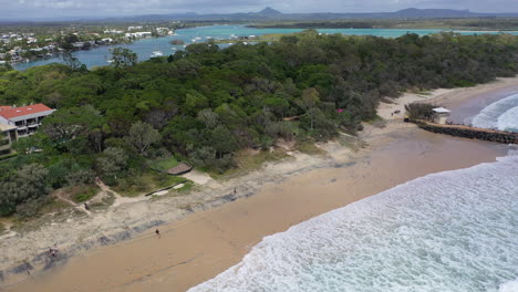 aerial footage along the beach at noosa flying over the lifeguard station and wave breaker