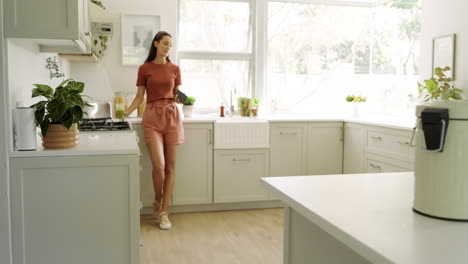 smiling woman in kitchen using smartphone, enjoying leisure time at home