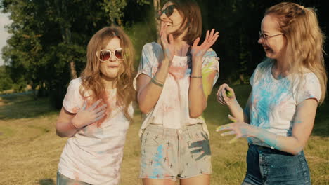 happy women friends celebrating a festival with colored powder
