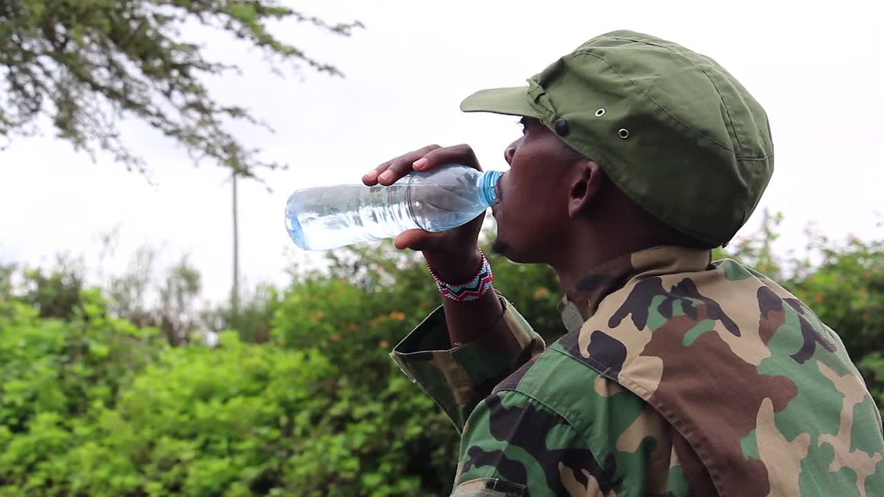 la guerrilla militante africana comprueba su cantidad de agua antes de beber en un día caluroso