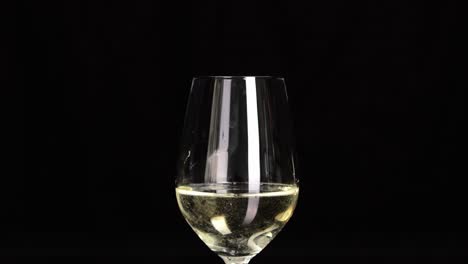 white wine in beautiful wineglass isolated on black background