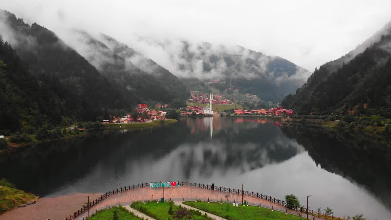 Fly over backwards reveal beautiful lake in Uzungol misty mountains village, Trabzon, Turkey
