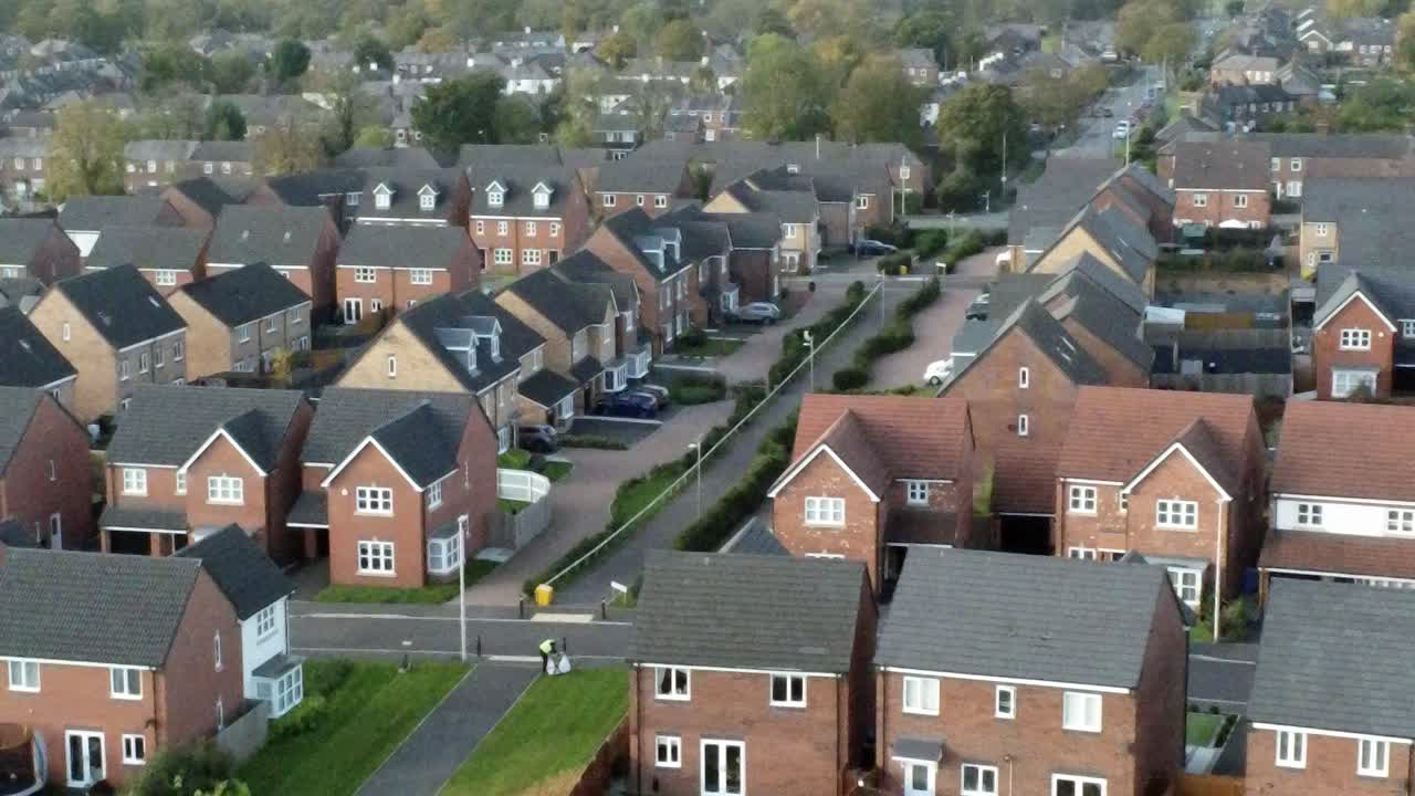 Property ladder new British housing estate aerial view overlooking rooftops moving left