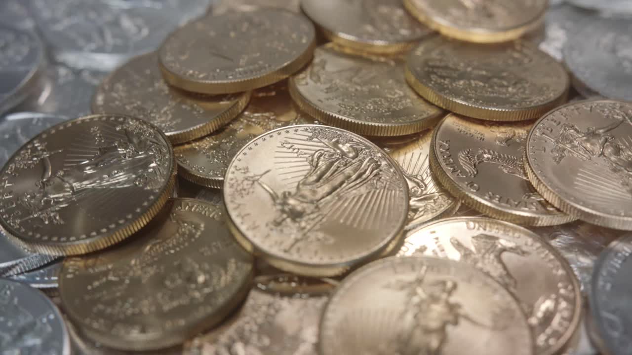 monedas de águilas doradas americanas en una pila de monedas de plata girando a la izquierda