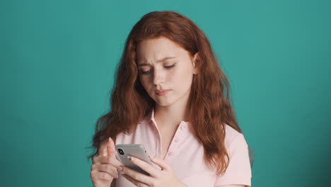 redheaded girl in front of camera on turquoise background.